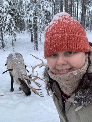 Louisa standing in the snow at Lapland next to a reindeer