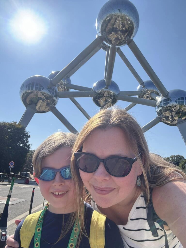 Photo of Louisa and her son (he is 8 and is wearing a sunflower lanyard) in front of the Atomium in Brussels