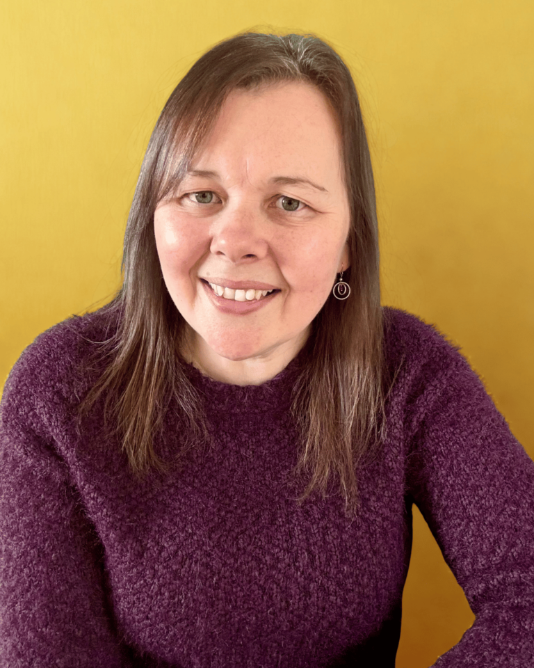 Lousia van Vessem wearing a purple jumper in front of a yellow/gold back ground